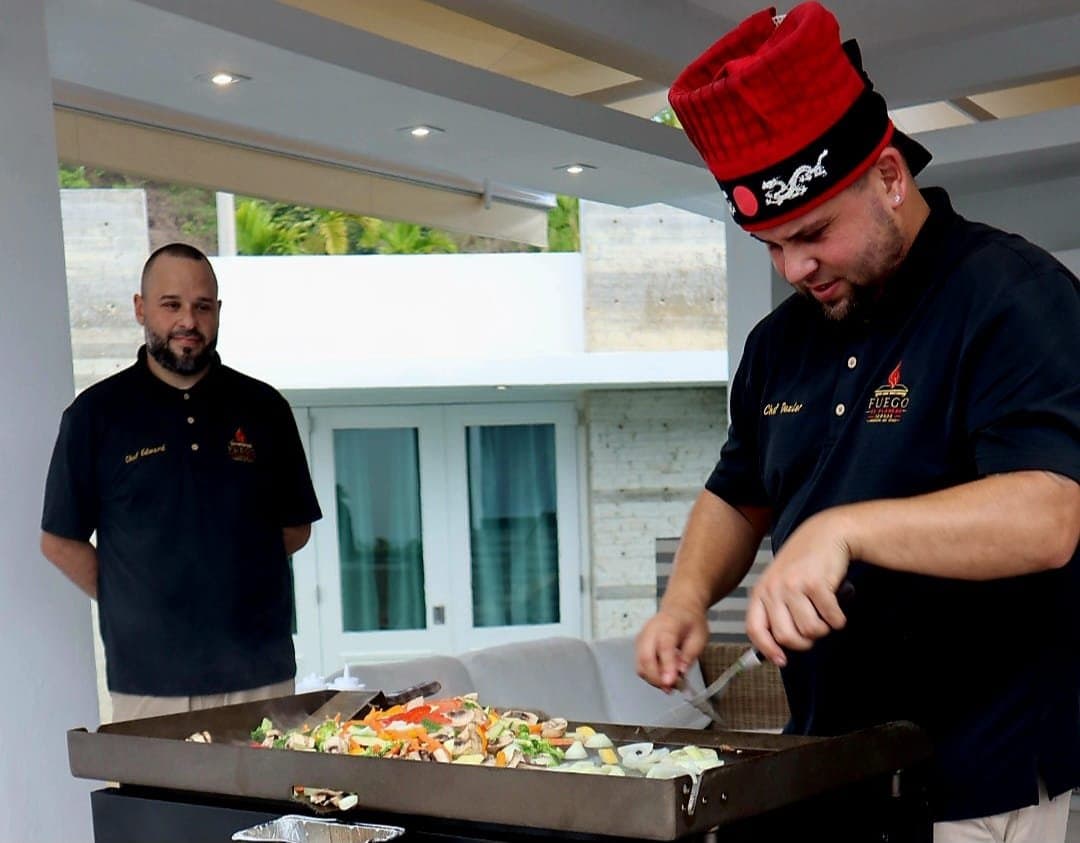 Chef Dexler cocinando vegetales en la plancha mientras Chef Edward observa
